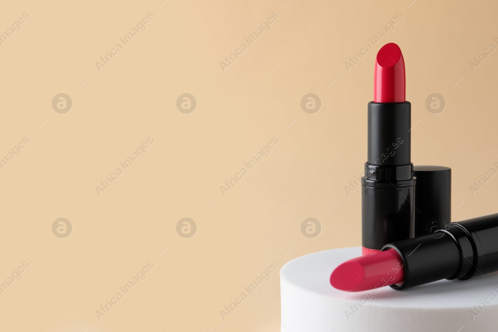 Photo of Beautiful pink lipsticks on beige background, space for text