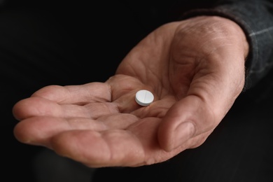 Photo of Senior man holding pill in his hand, closeup