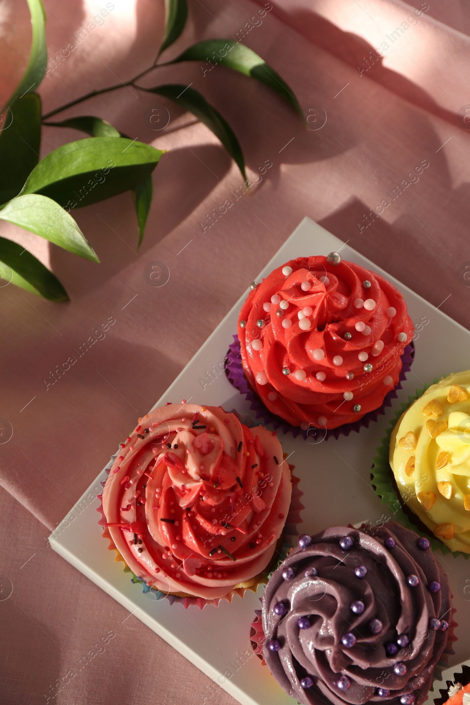 Photo of Delicious cupcake with bright cream on pink fabric