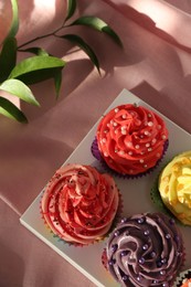 Photo of Delicious cupcake with bright cream on pink fabric