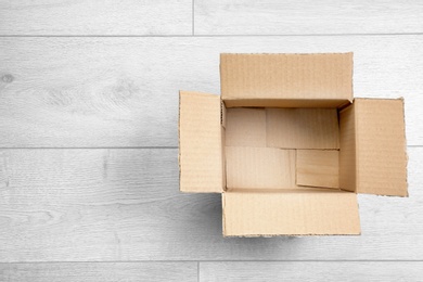 Photo of Open empty cardboard box on wooden floor