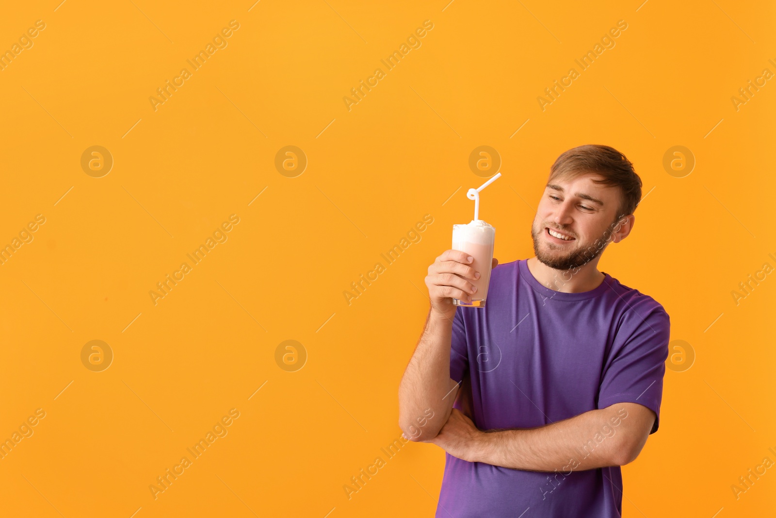 Photo of Young man with glass of delicious milk shake on color background