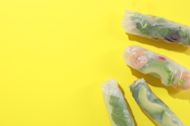 Photo of Delicious spring rolls wrapped in rice paper on yellow background, flat lay. Space for text