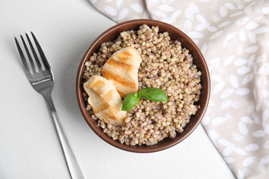 Tasty buckwheat porridge with meat on white table, flat lay