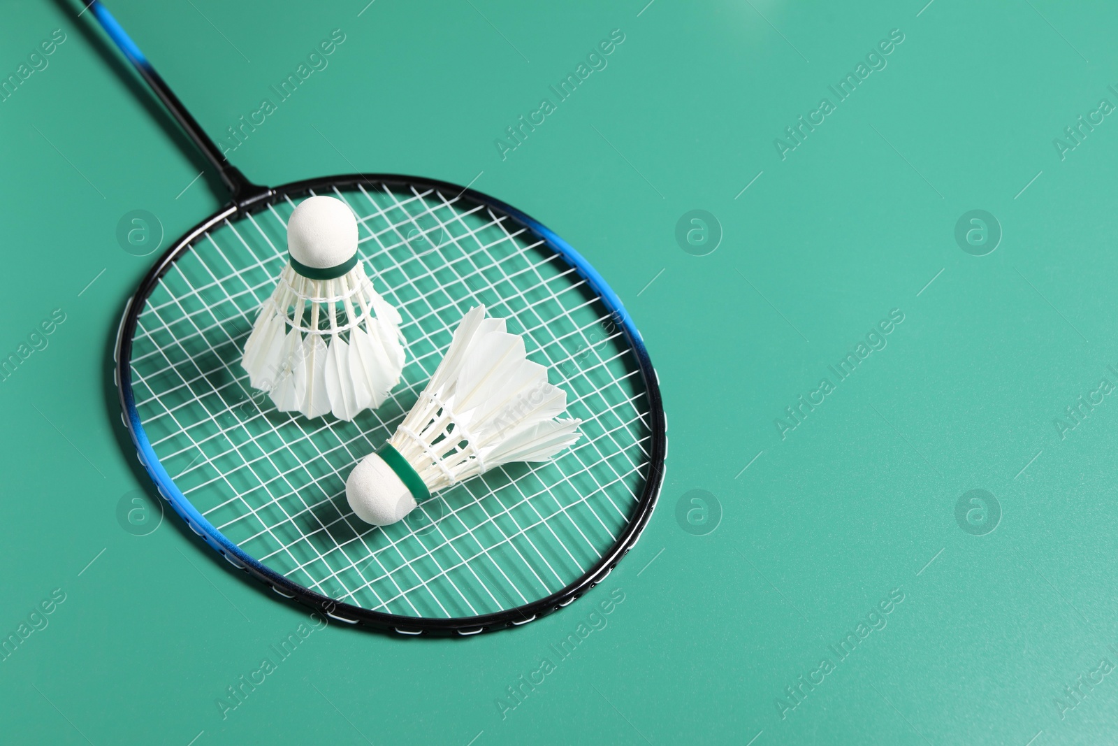 Photo of Feather badminton shuttlecocks and racket on green background. Space for text