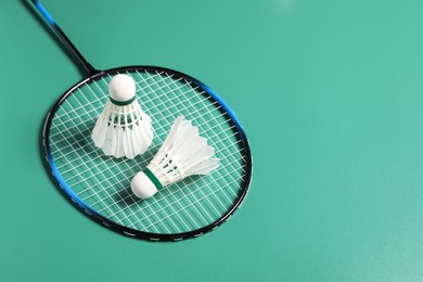 Photo of Feather badminton shuttlecocks and racket on green background. Space for text