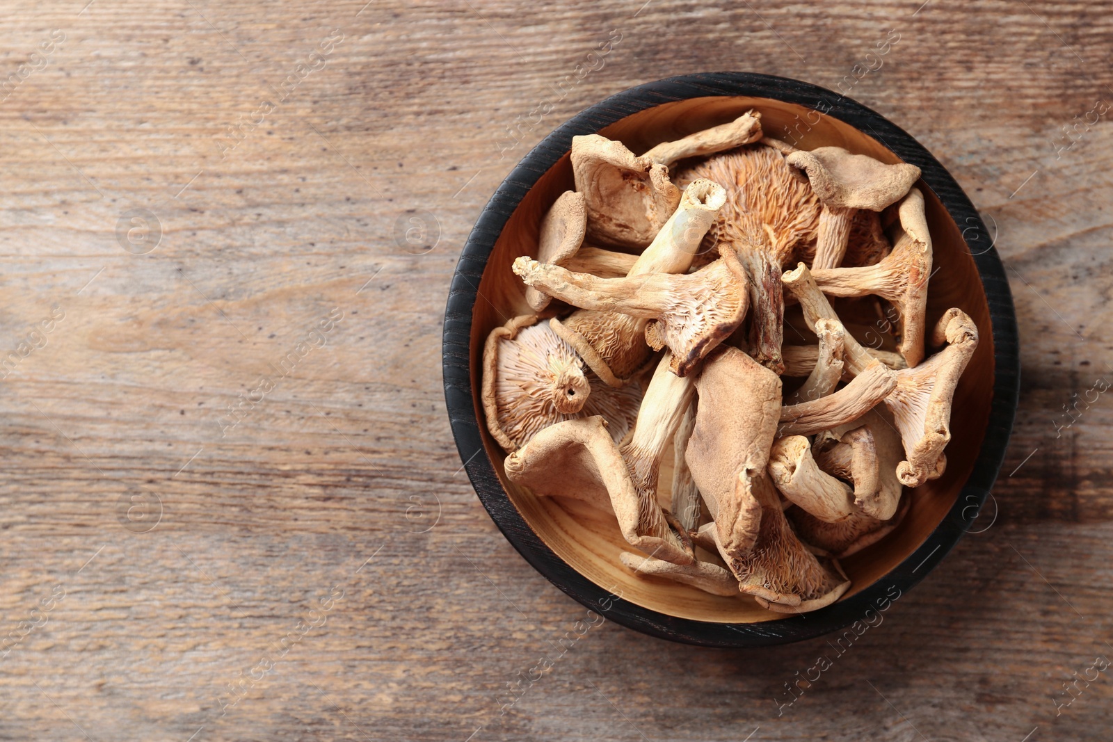 Photo of Plate of dried mushrooms on wooden background, top view. Space for text