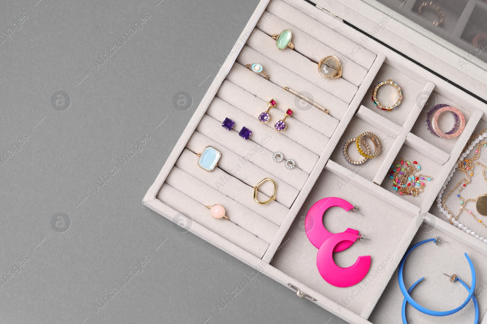 Photo of Jewelry box with many different accessories on gray background, top view. Space for text