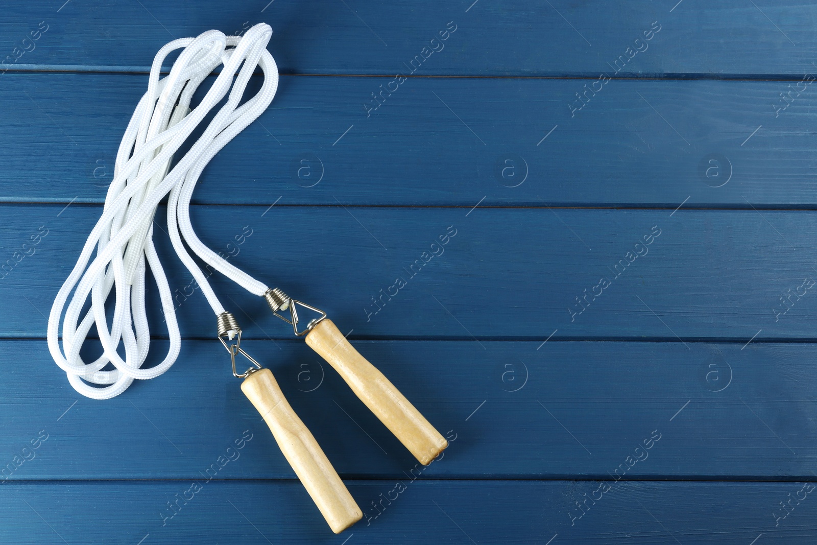 Photo of Skipping rope on blue wooden table, top view. Space for text