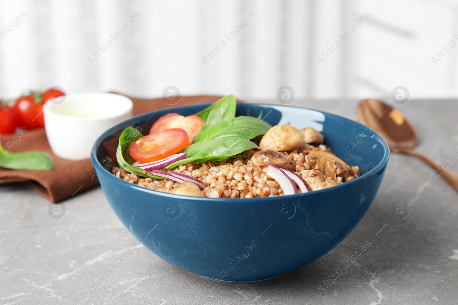 Photo of Tasty buckwheat porridge with vegetables and mushrooms on table indoors