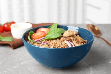 Tasty buckwheat porridge with vegetables and mushrooms on table indoors