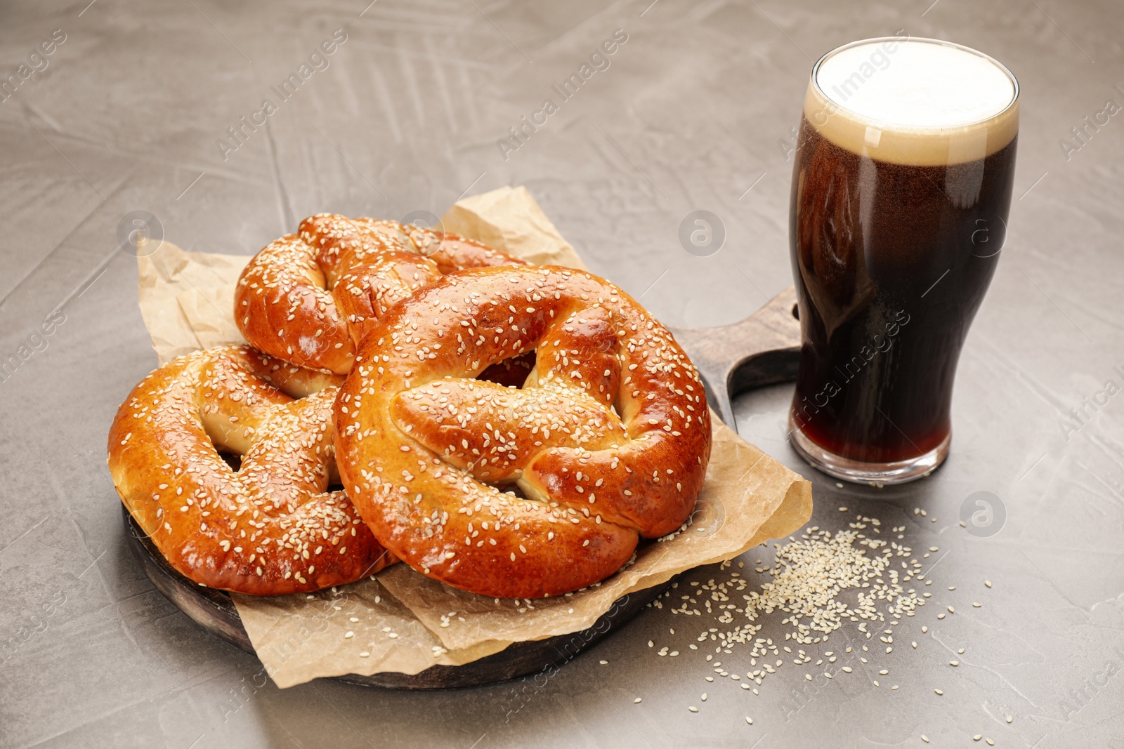 Photo of Tasty pretzels and glass of beer on grey table