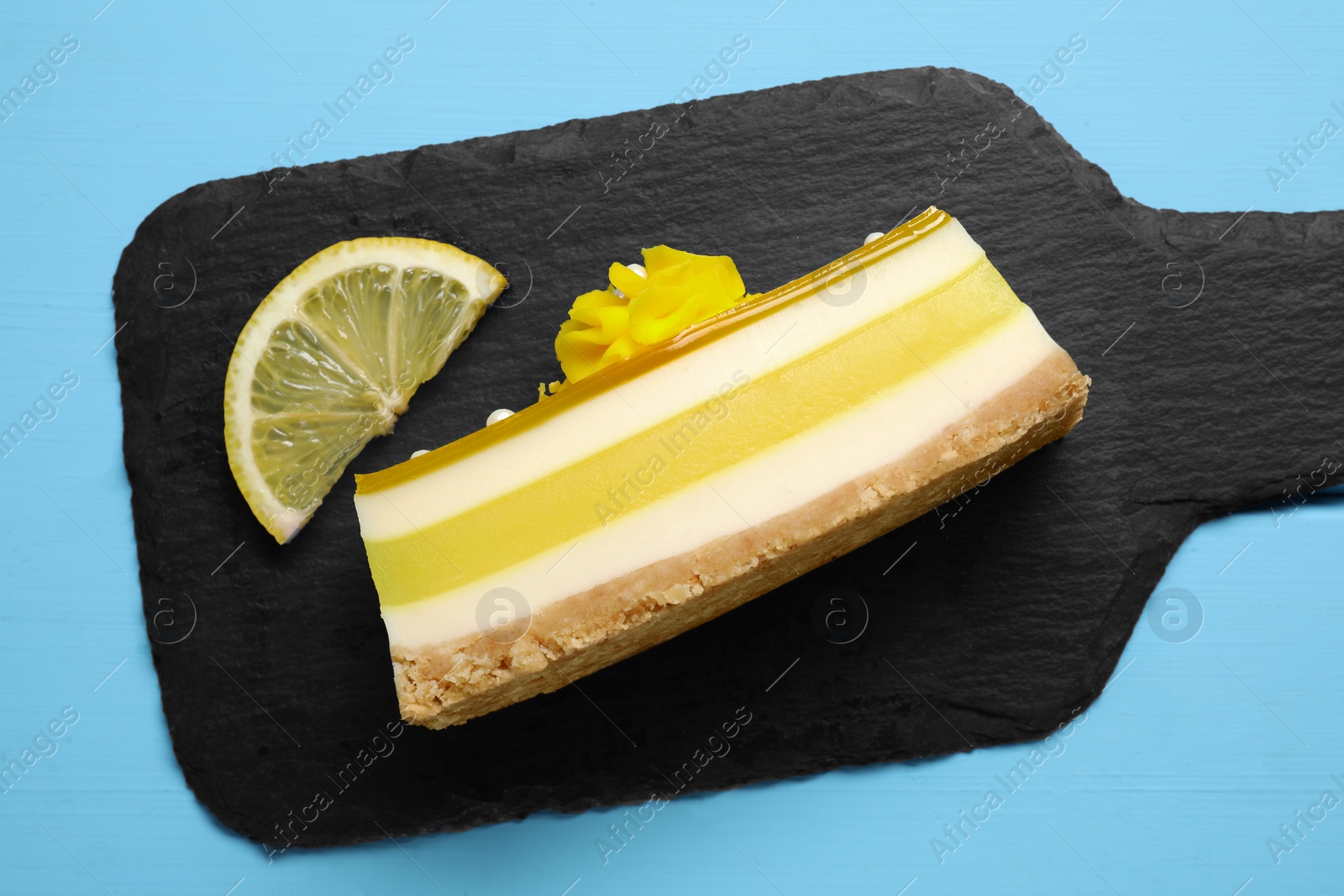 Photo of Delicious cheesecake with lemon on light blue wooden table, top view