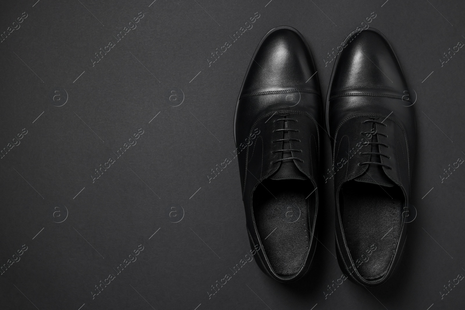 Photo of Pair of leather men shoes on black background, top view. Space for text