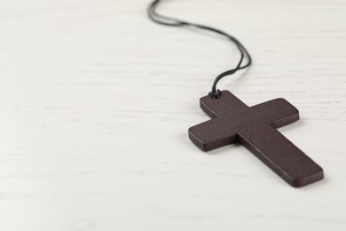 Photo of Christian cross on white wooden table, closeup. Space for text