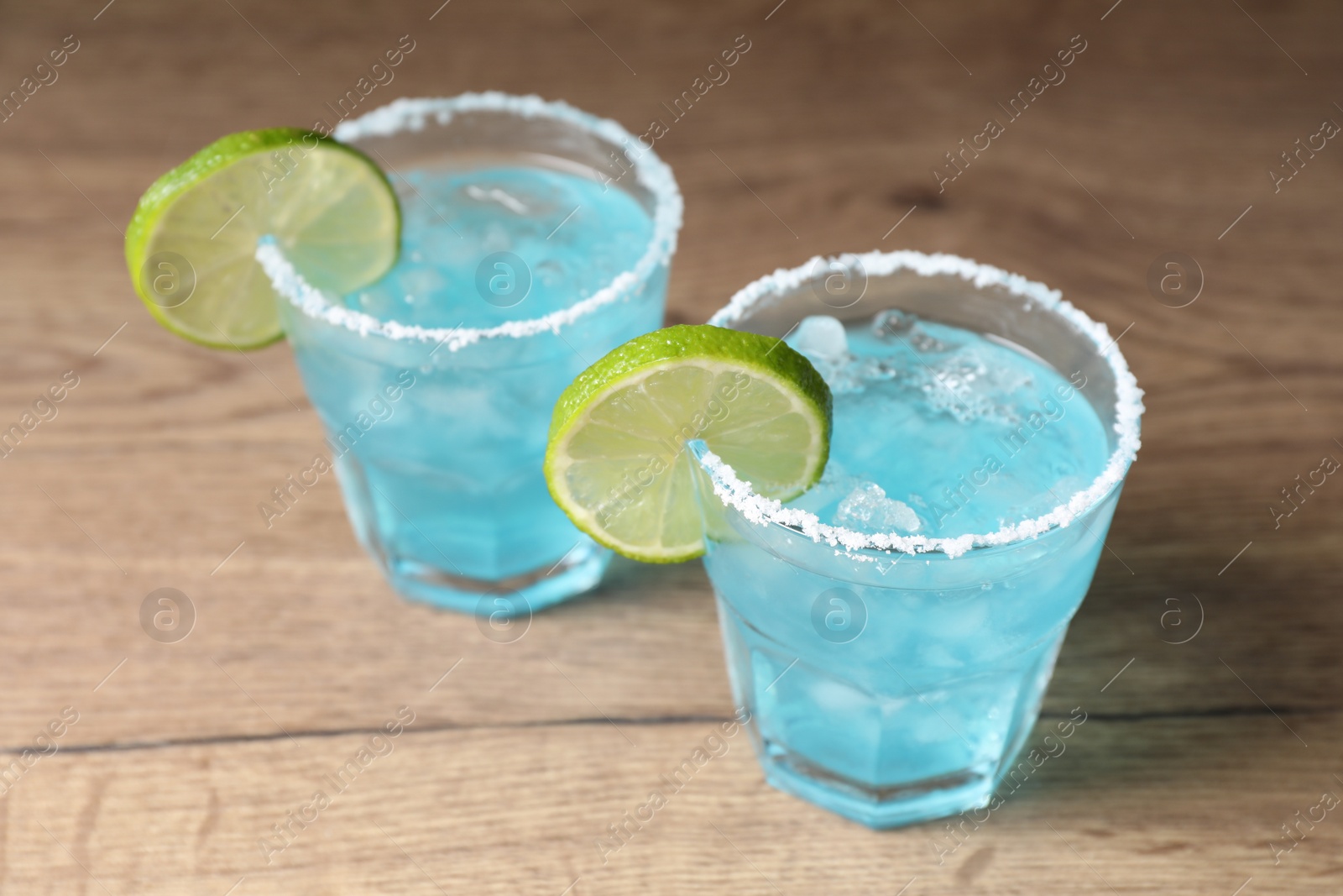 Photo of Refreshing light blue cocktail on wooden table