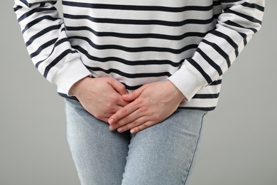 Photo of Woman suffering from cystitis on grey background, closeup