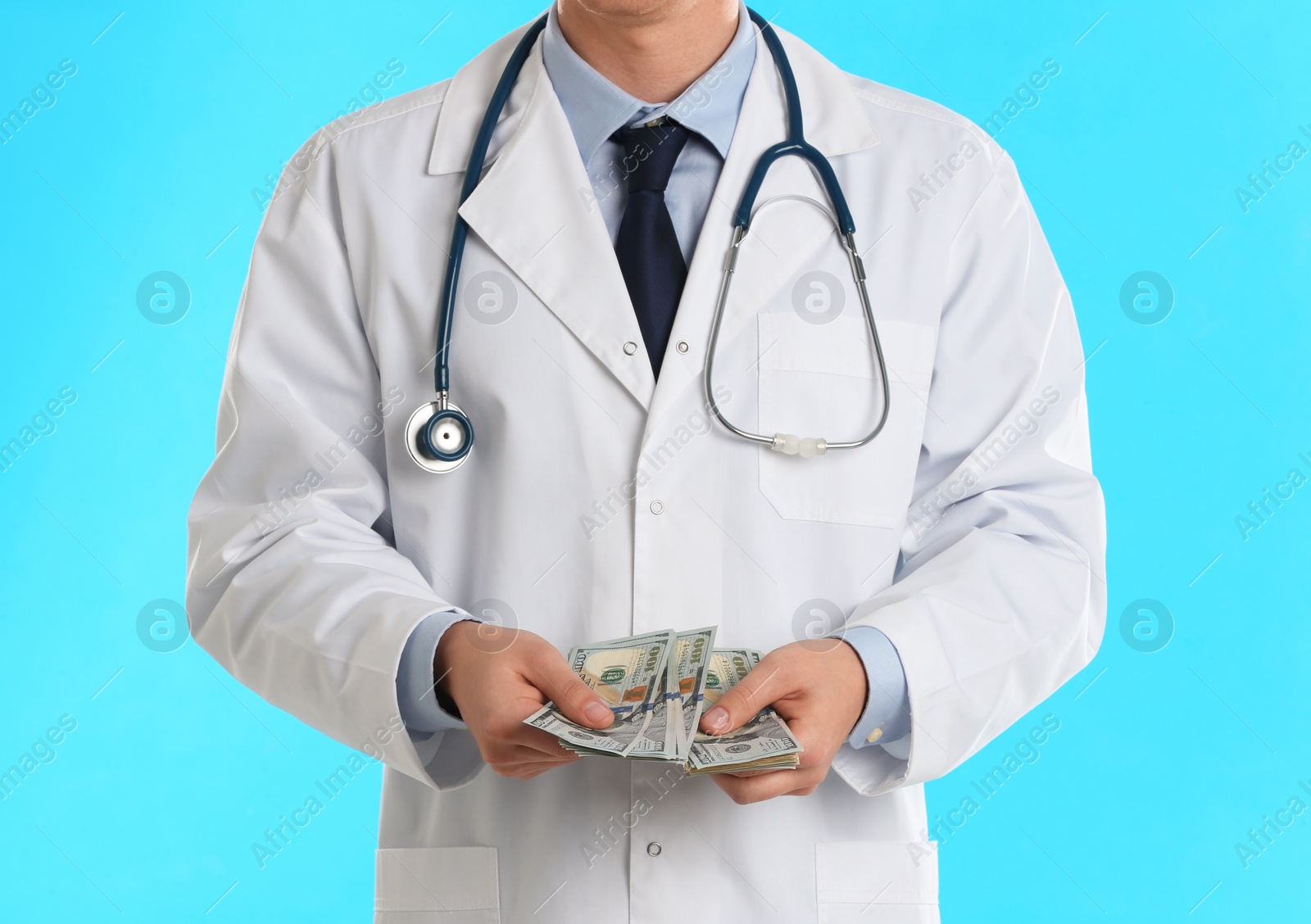Photo of Doctor with bribe on light blue background, closeup. Corruption in medicine