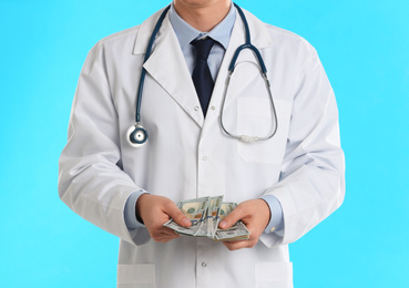 Photo of Doctor with bribe on light blue background, closeup. Corruption in medicine