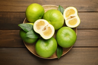 Photo of Whole and cut sweetie fruits on wooden table, top view