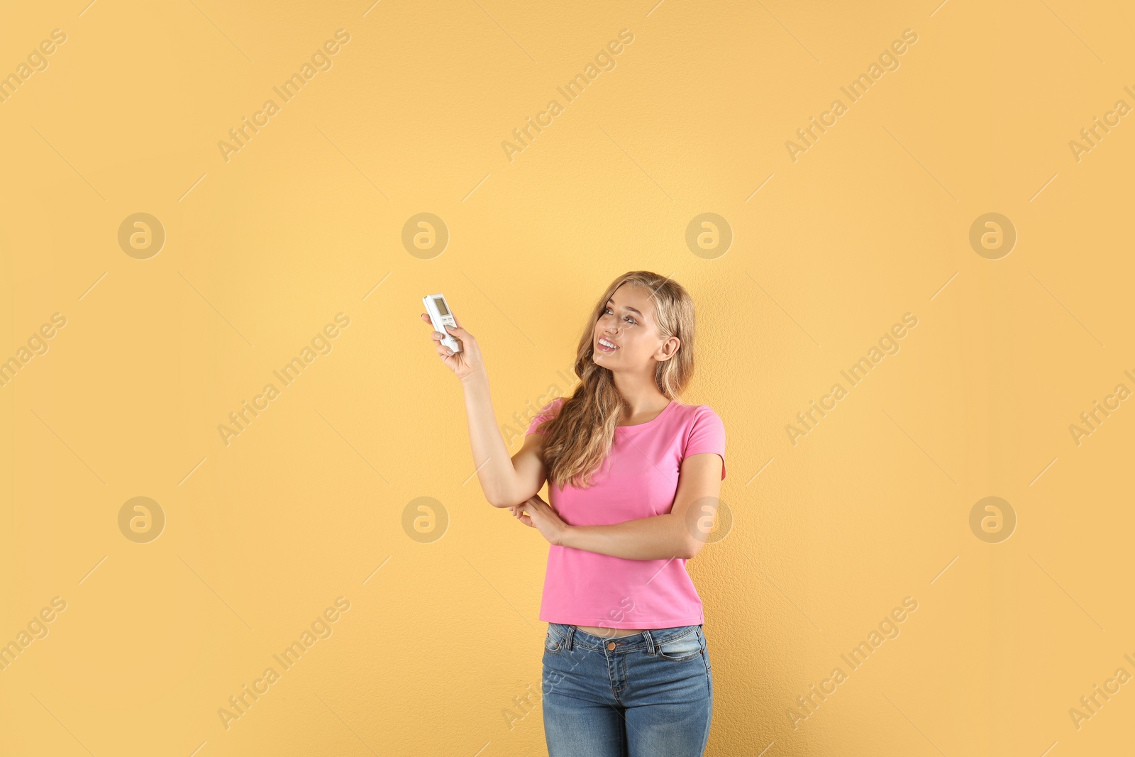 Photo of Young woman with air conditioner remote on color background