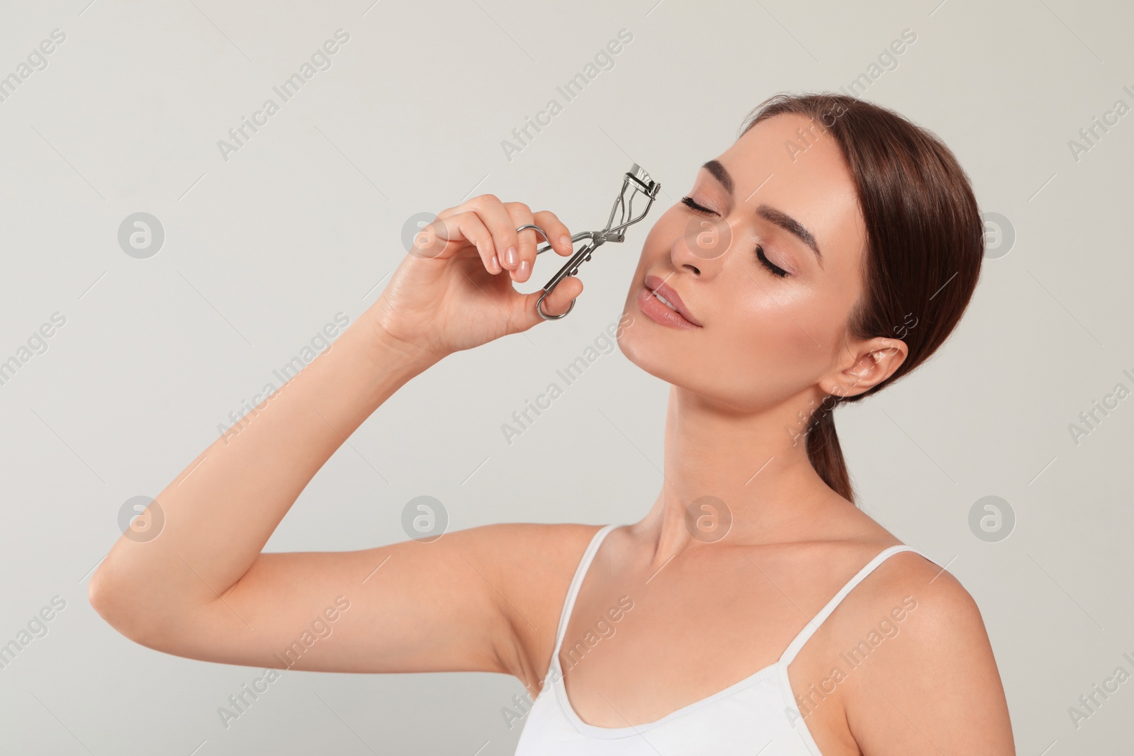 Photo of Woman with eyelash curler on white background