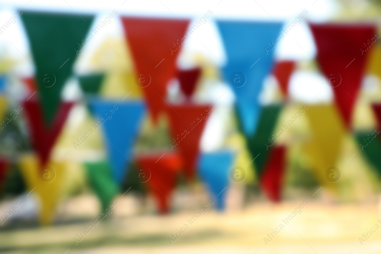 Photo of Blurred view of colorful bunting flags in park. Party decor