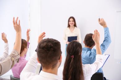 Photo of People raising hands to ask questions at business training indoors