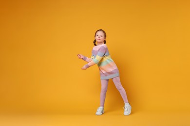 Cute little girl dancing on orange background