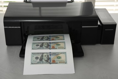 Photo of Printing dollar banknotes on grey table. Fake money concept