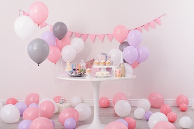 Party treats and items on table in room decorated with balloons