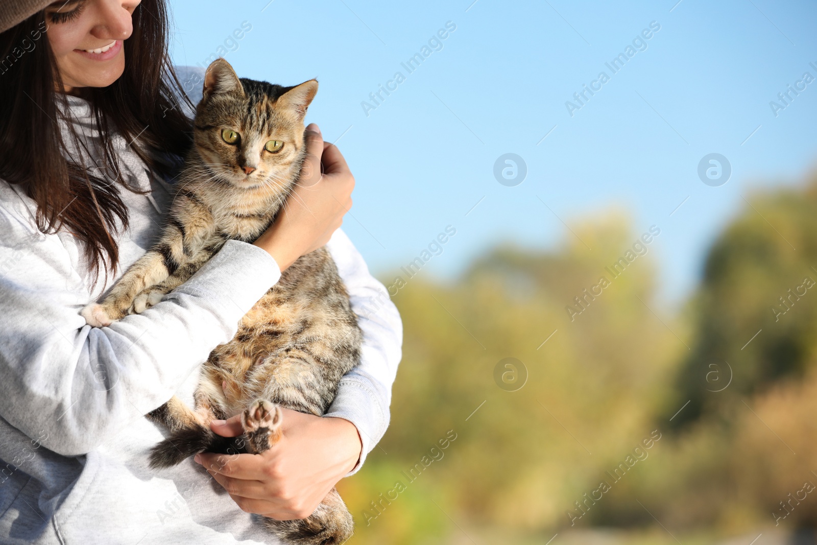 Photo of Woman with cute cat outdoors. Space for text