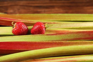 Photo of Many fresh rhubarb stalks and strawberries as background, closeup