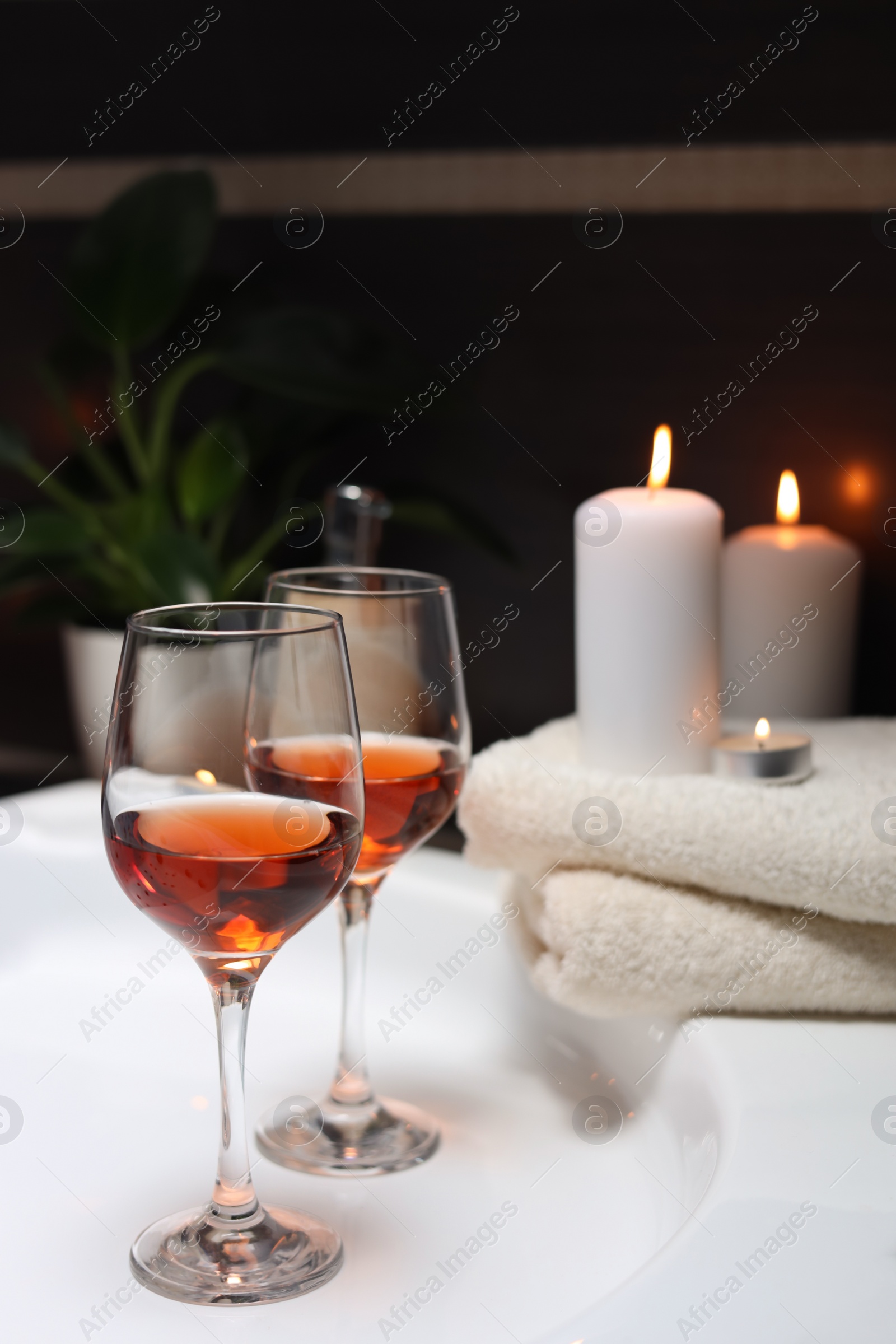 Photo of Bathtub with glasses of wine and candles indoors. Romantic atmosphere