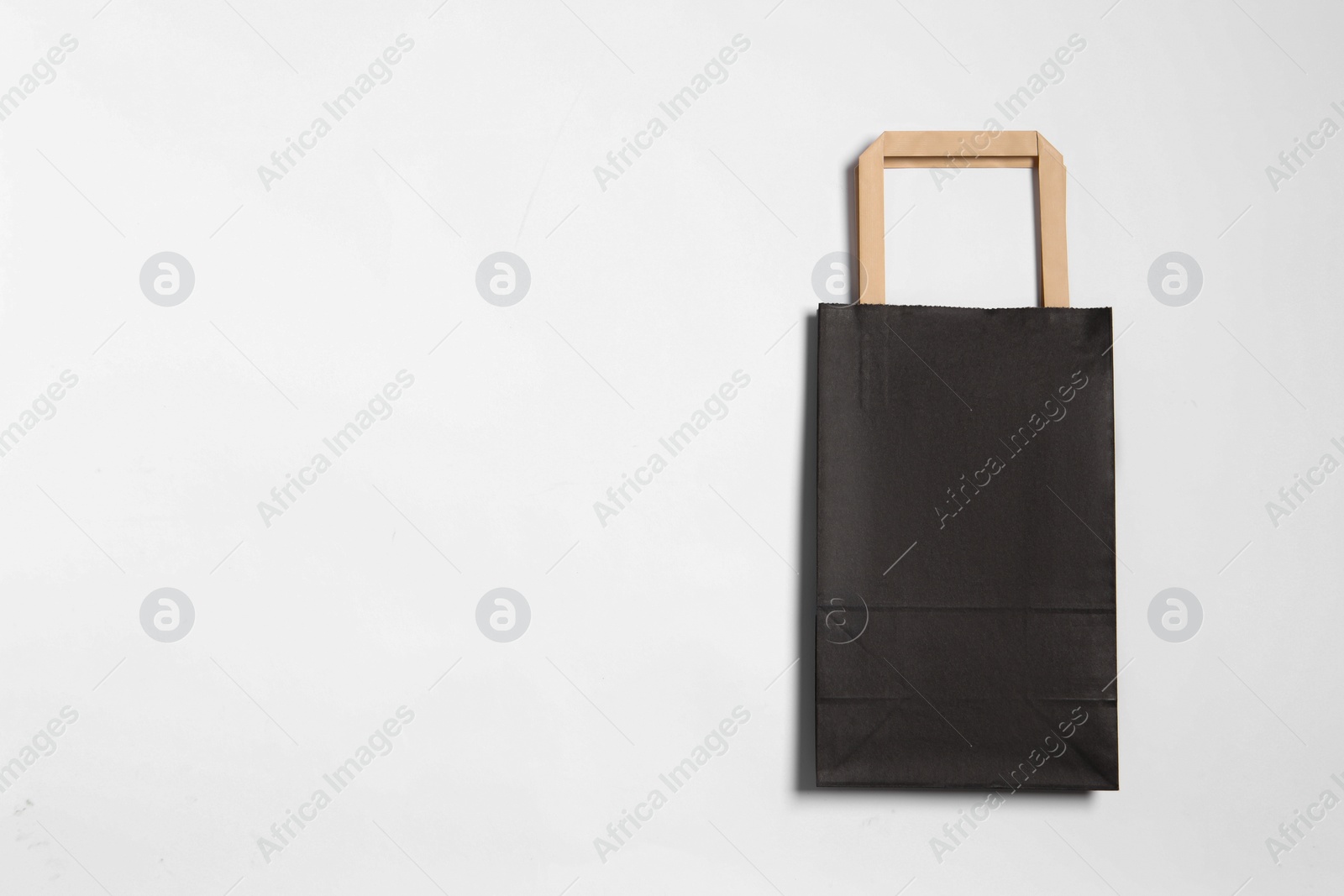 Photo of One black paper shopping bag on white background, top view. Space for text