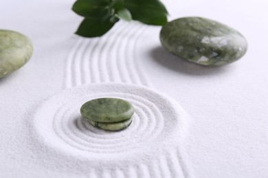 Photo of Zen concept. Stones, leaves and pattern on white sand, closeup