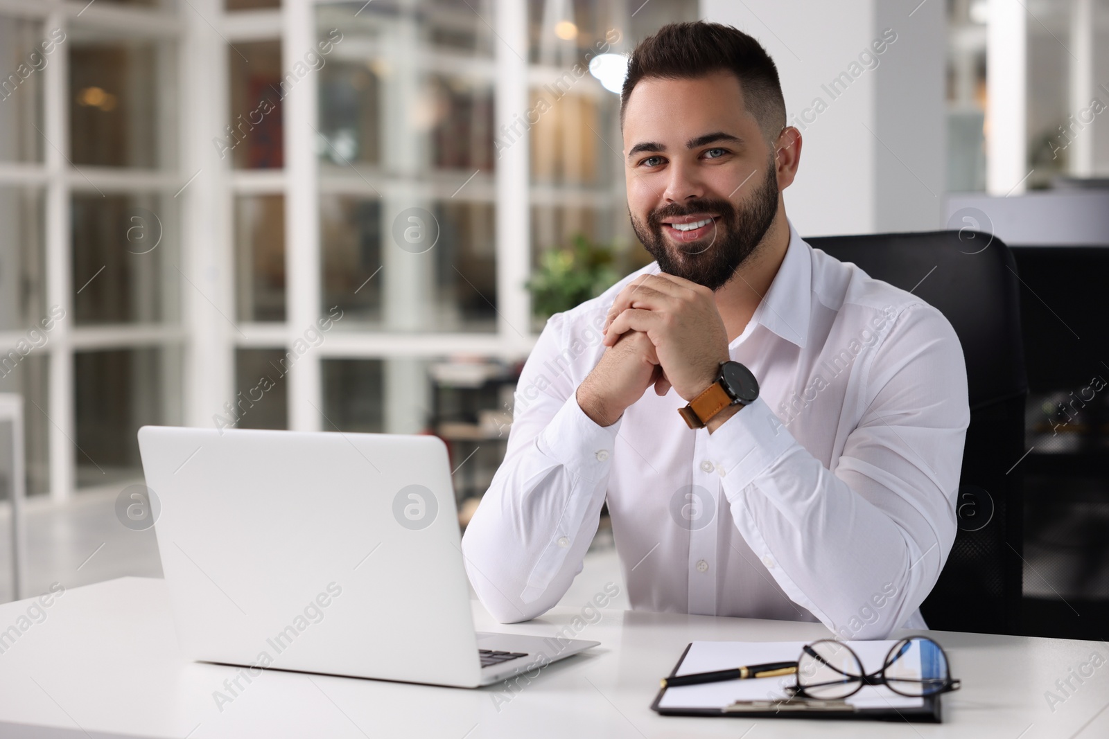 Photo of Portrait of smiling man at table in office. Lawyer, businessman, accountant or manager