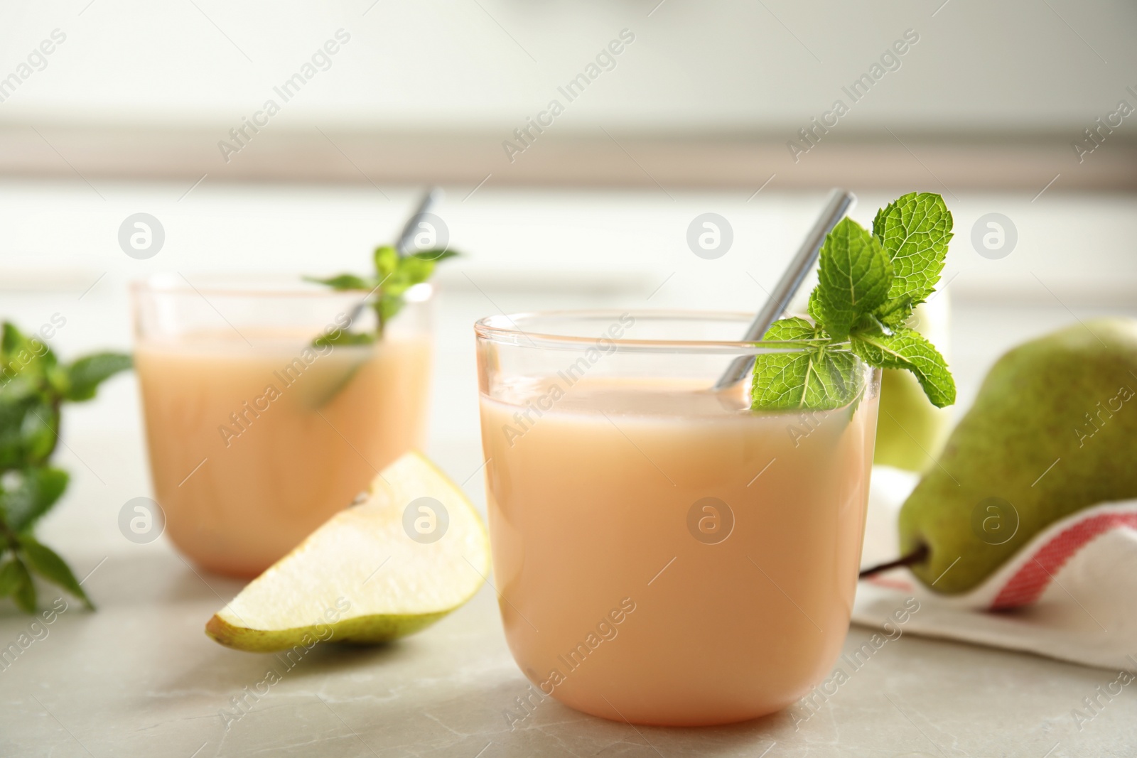 Photo of Tasty pear juice with mint on light grey table, closeup