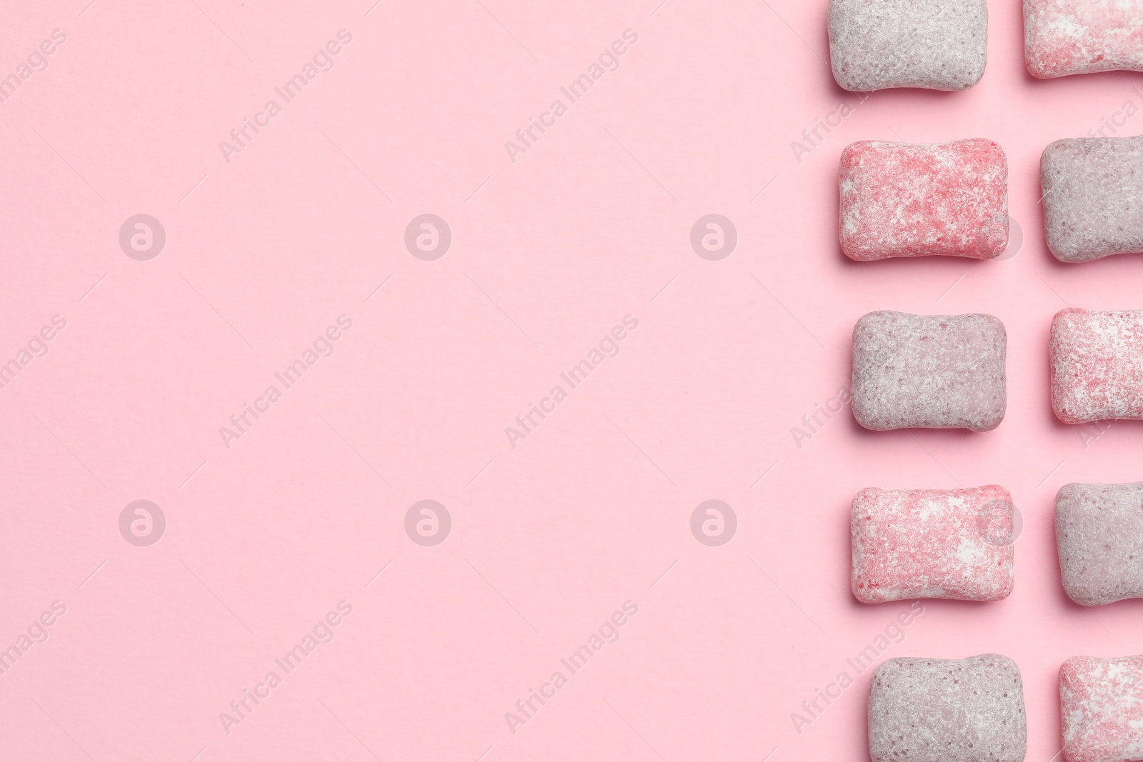 Photo of Tasty colorful bubble gums on pink background, flat lay. Space for text