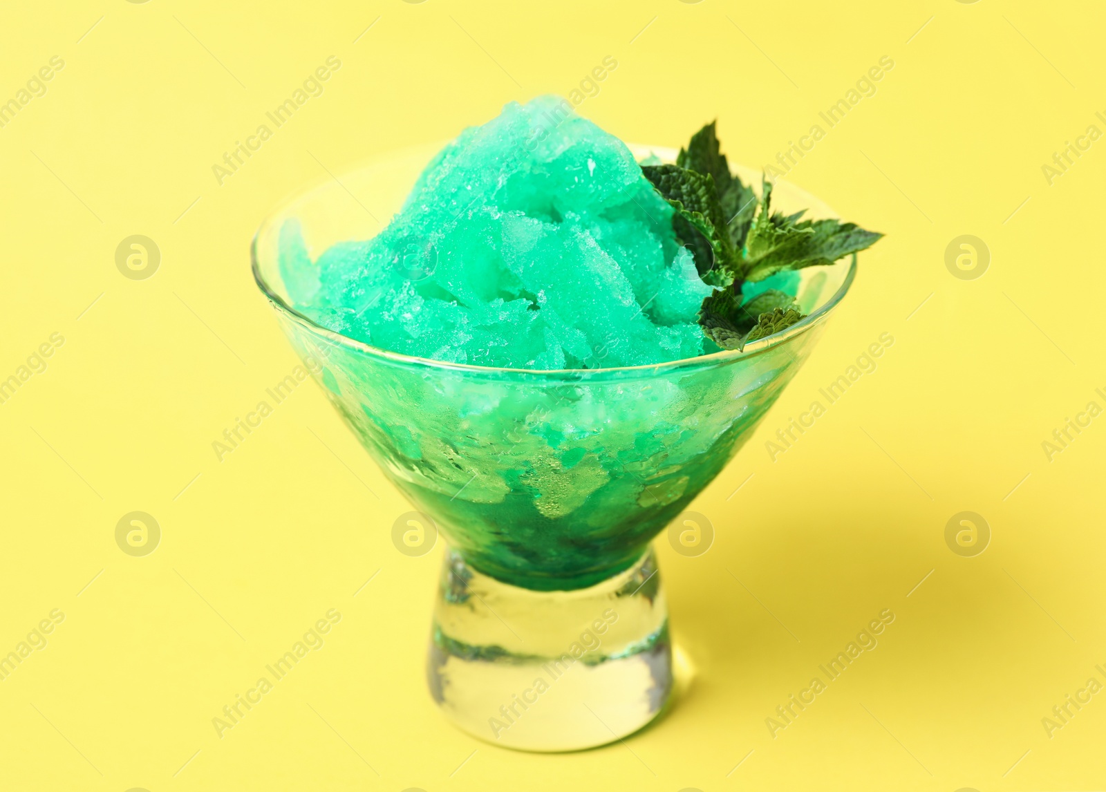 Photo of Shaving ice in glass dessert bowl on yellow background, closeup