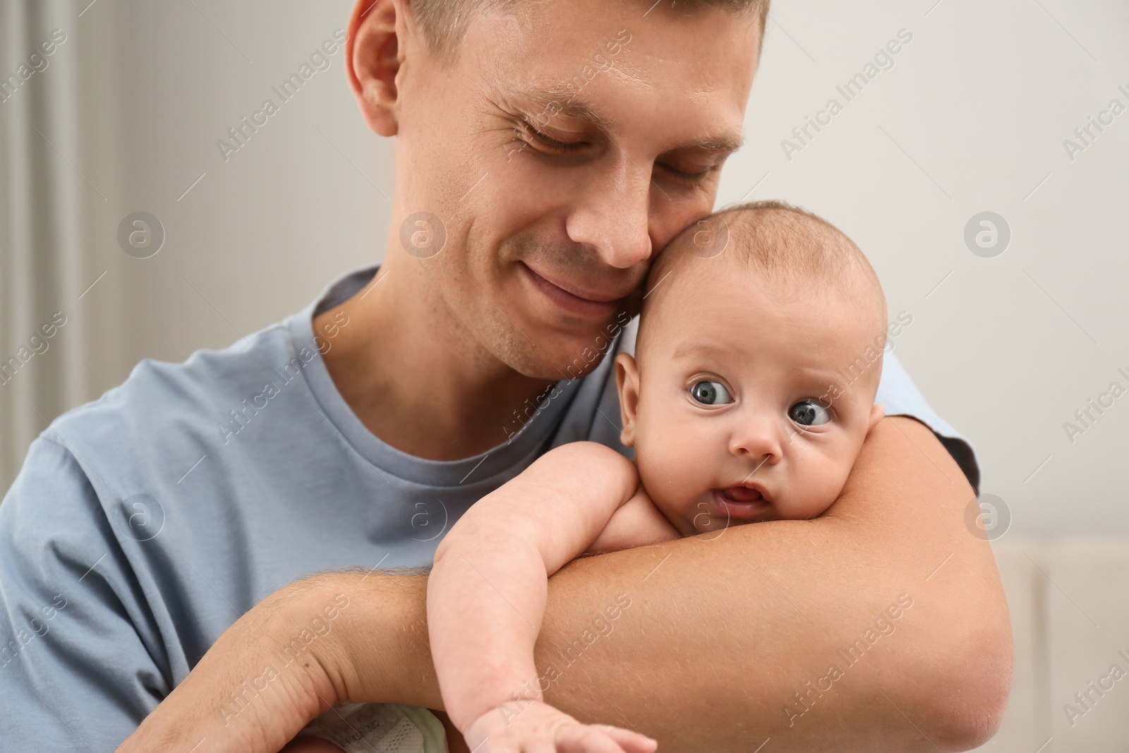 Photo of Happy father holding his cute baby at home, closeup