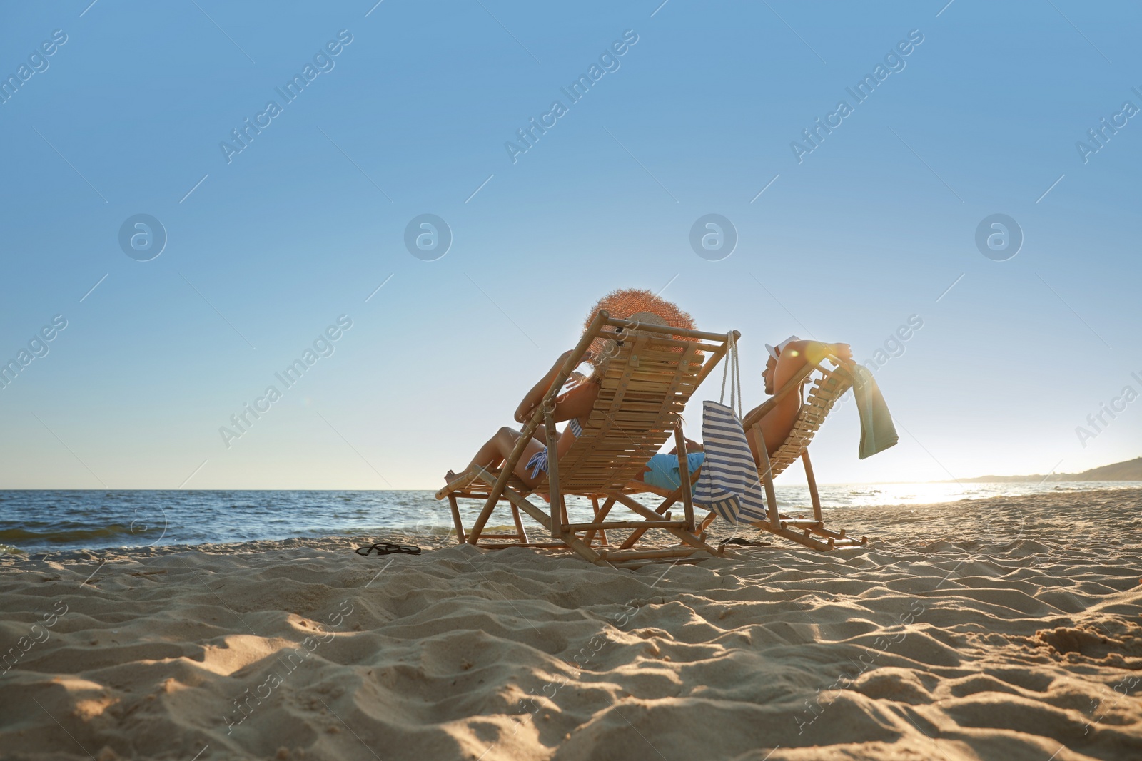 Photo of Young couple relaxing in deck chairs on beach near sea