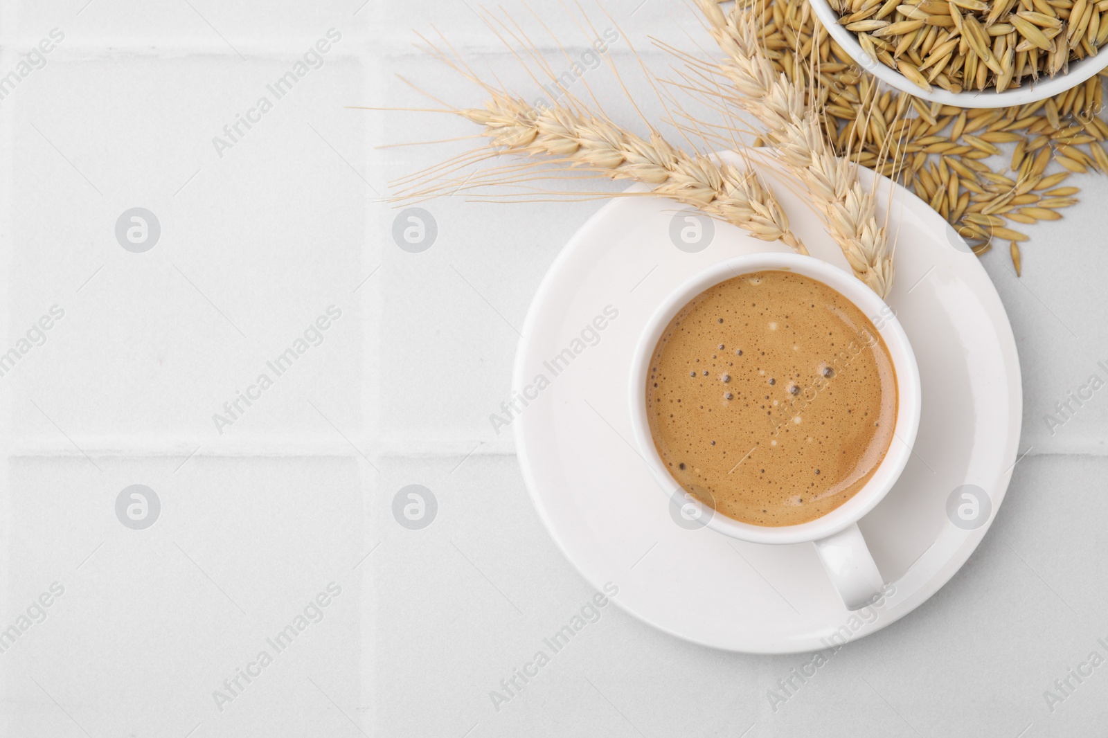 Photo of Cup of barley coffee, grains and spikes on white table, flat lay. Space for text