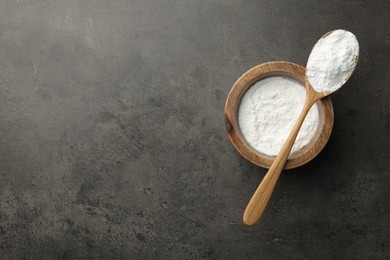 Photo of Baking powder in bowl and spoon on grey textured table, top view. Space for text