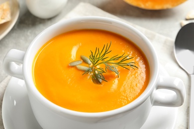 Photo of Delicious pumpkin cream soup in bowl on table, closeup