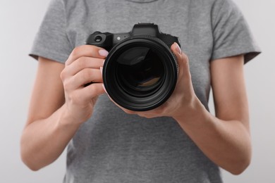 Photo of Photographer with camera on light grey background, closeup