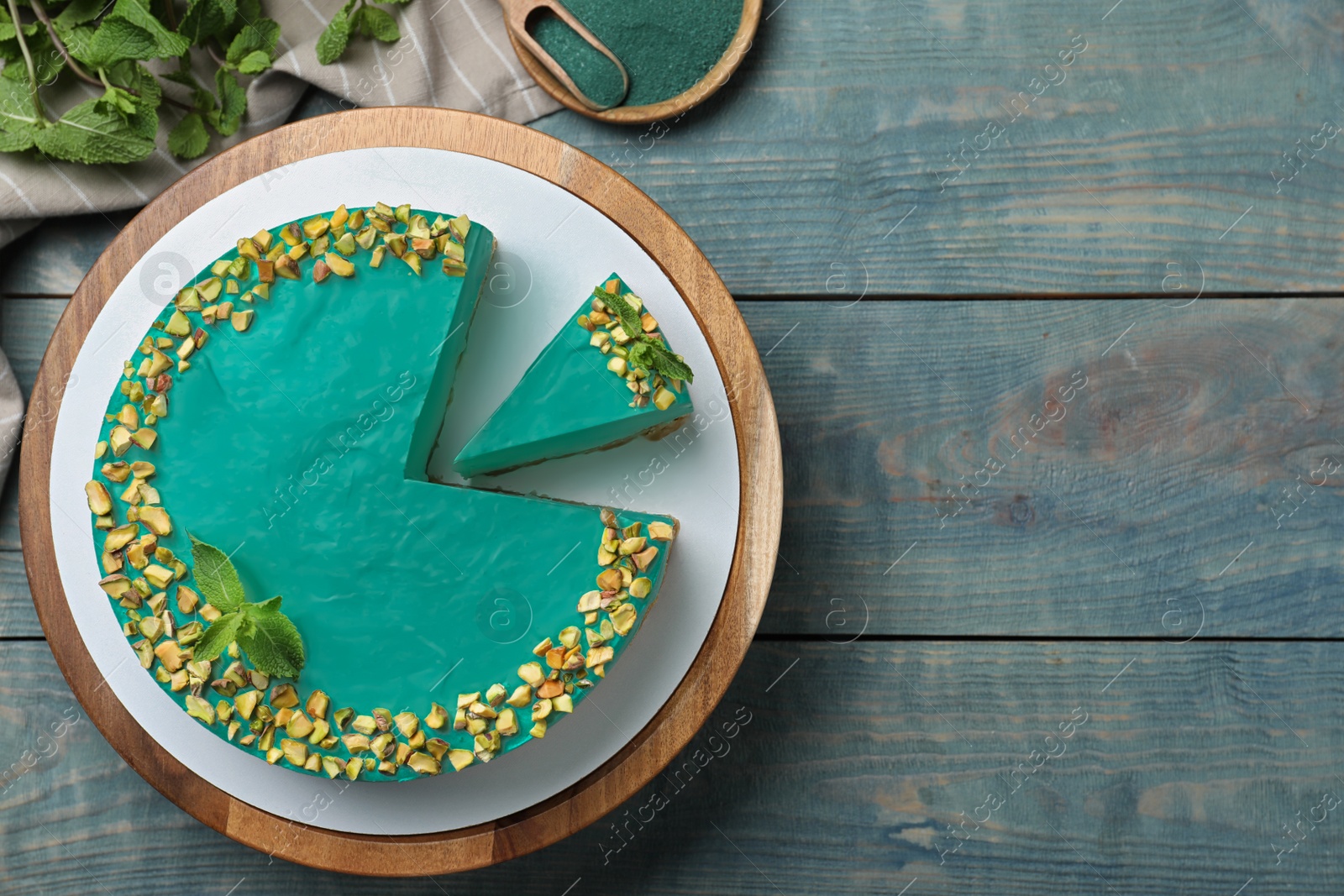 Photo of Flat lay composition with tasty spirulina cheesecake on blue wooden table, space for text