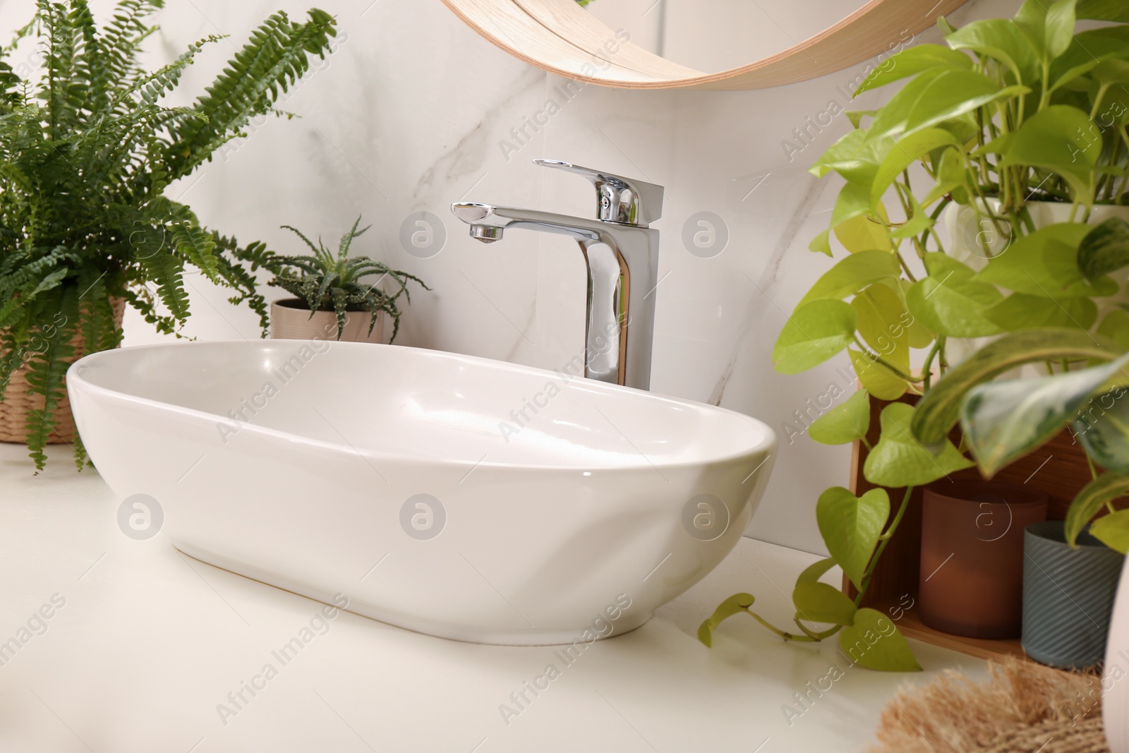 Photo of Bathroom counter with sink and beautiful green houseplants near white marble wall