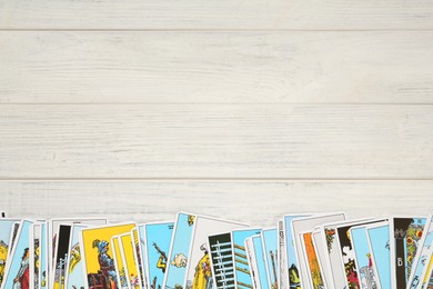 Photo of Tarot cards on white wooden table, top view. Space for text