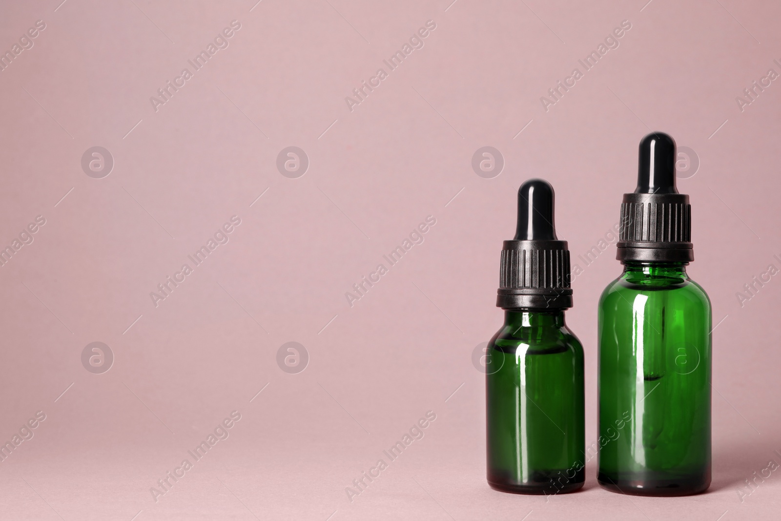 Photo of Cosmetic bottles of essential oils on color background. Space for text